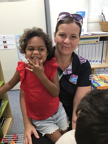 Kylie sitting with a student, smiling happily.