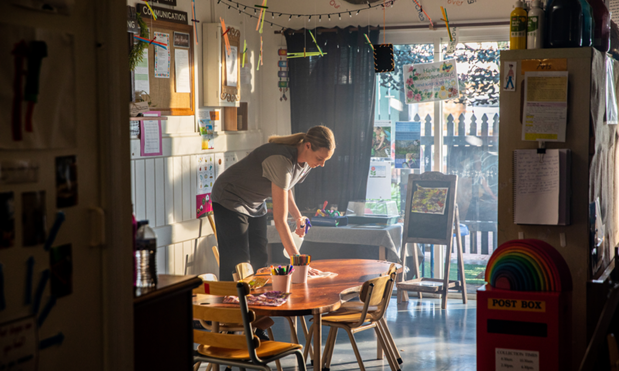 An educator is cleaning her early learning centre with a cloth.