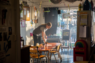An educator is cleaning her early learning centre with a cloth.